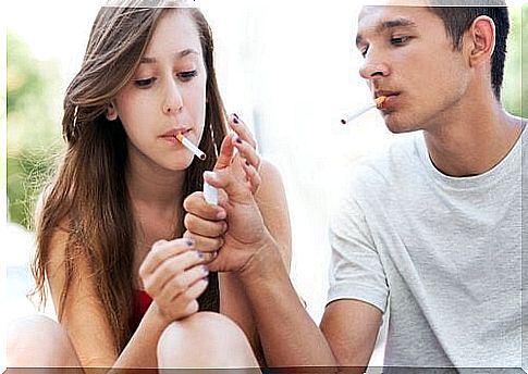 A young person lights his friend's cigarette