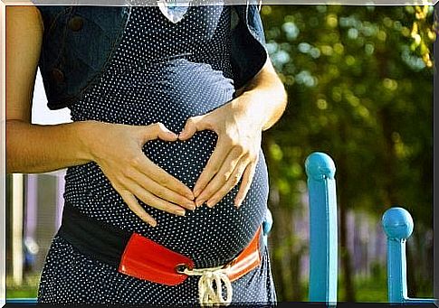 A woman forms a heart on her belly