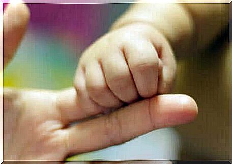 A baby holding a finger.