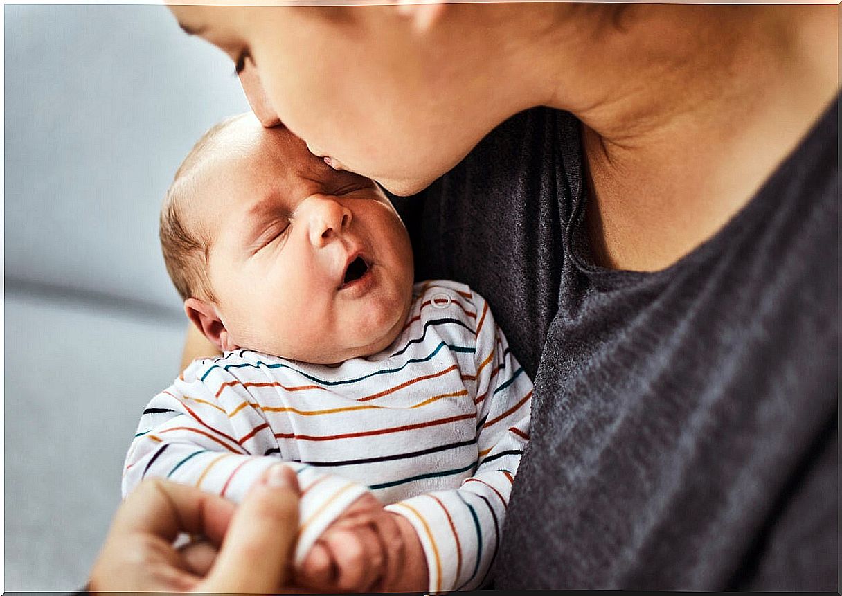 Mother kissing her baby on the forehead.