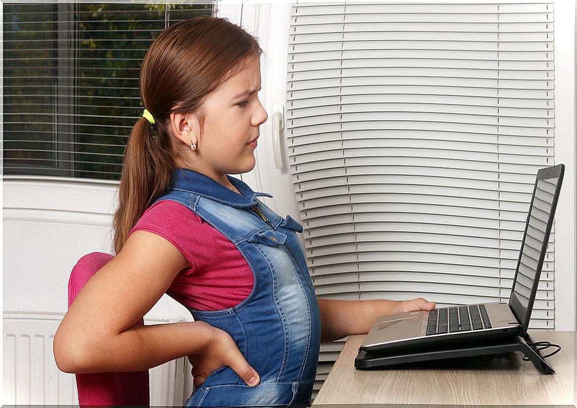 Young girl suffering from low back pain in front of her computer. 