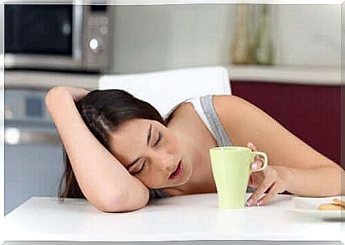 A young girl sleeping in front of her cup of coffee