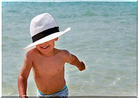 A child with a hat at the beach. 