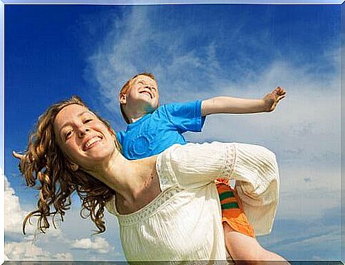 A mother carries her son on her shoulders