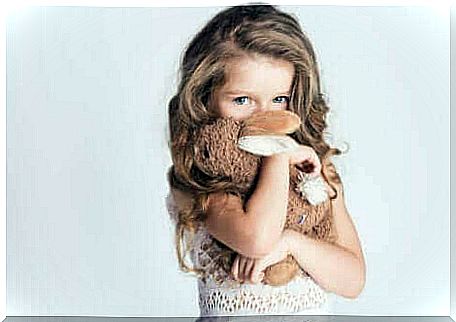 A girl hiding behind her soft toy.