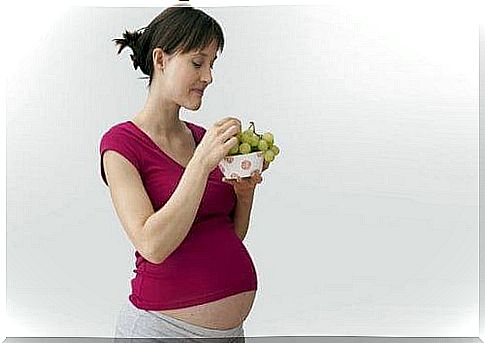 A pregnant woman eats grapes