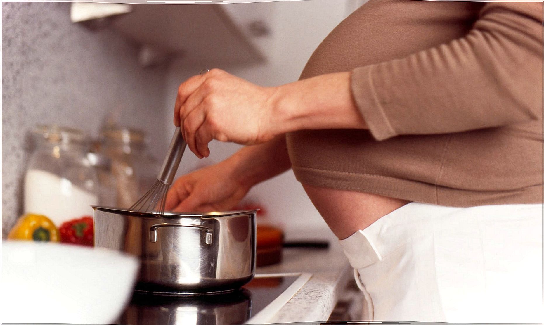 A pregnant woman is cooking.