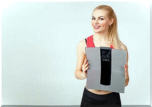 A woman holding a weighing scale.