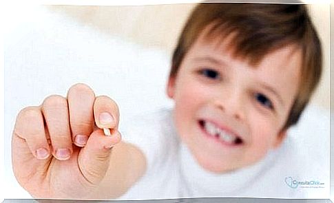 A little boy shows one of his teeth which has fallen out