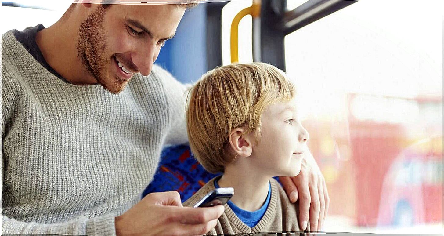 A father on his phone on the bus with his son